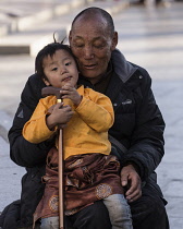 A grandfather and his grandchild sit at Barkhor Square in Lhasa, Tibet.