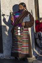 A Khamba Tibetan woman from the Kham region of eastern Tibet on a pilgrimage to the Jokhang Temple in Lhasa, Tibet.  She is wearing a traditional heavy sheepskin-lined chupa or chuba coat and gangdian...