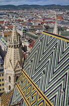 Austria, Vienna, Stephansdom or St Stephens Cathedral, View of the colourful roof tiles from the South Tower with Vienna in the background.