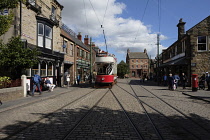 England, County Durham, Beamish, Street with electric tram full of tourists.