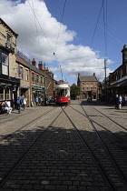 England, County Durham, Beamish, Street with electric tram full of tourists.