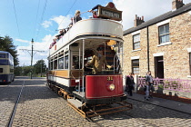 England, County Durham, Beamish, Street with electric tram full of tourists.