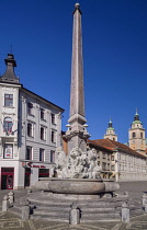 Slovenia, Ljubljana, Full length view of the Robba Fountain with towers and dome of the Cathedral of St Nicholas in the background.