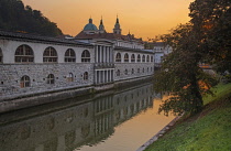 Slovenia, Ljubljana, Plecnik Colonnade and Central Market at sunset with the Cathedral of St Nicholas behind and the Ljubljanica River in the foreground.