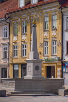 Slovenia, Upper Carniola, Kranj, Fountain on Glavni trg which is the Old Towns main square with pastel coloured buildings in the background.