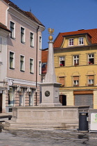 Slovenia, Upper Carniola, Kranj, Fountain on Glavni trg which is the Old Towns main square with pastel coloured buildings in the background.