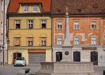 Slovenia, Upper Carniola, Kranj, Fountain on Glavni trg which is the Old Towns main square with pastel coloured buildings in the background.