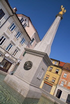 Slovenia, Upper Carniola, Kranj, Low angular view of the fountain on Glavni trg which is the Old Towns main square with pastel coloured houses in the background.