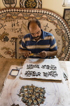 Jordan, Madaba, Handicraft Center Mosaic Workshop, A mosaicist at the Handicraft Center Mosaic Workshop uses nippers to shape the pieces of tile for his mosaic piece in progress. All the mosaicists th...
