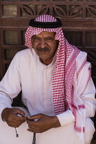 Jordan, Wadi Rum Protected Area, A Bedouin man wearing the traditional keffiyeh or kufiiya (head scarf), agal (rope headband) and thawb or robe. Wadi Rum Protected Area, a UNESCO World Heritage Site.
