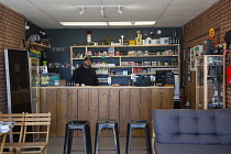England, East Sussex, Hove, E-cigarette store owner, Christopher Paul Streeter, of Dirty B's Vape shop using furniture to maintain social distancing during coronovirus emergency measures.