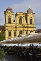 Romania, Timis, Timisoara, Cafes on Piata Uniri with Catholic cathedral, old town.