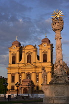 Romania, Timis, Timisoara, Catholic Cathedral and Holy Trinity column (monumnet to the plague) on Piata Uniri at sunset, old town.