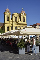 Romania, Timis, Timisoara, Cafes on Piata Uniri with Catholic cathedral, old town.