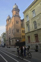 Romania, Timis, Timisoara, Synagogue 1864, late light illuminating the towers and facade, with cyclists and pedestrians, old town.