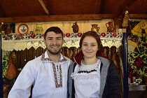 Romania, Timis, Timisoara, Maramures food stall and traditionally dressed couple, Spring market, Piata Victoriei, old town.
