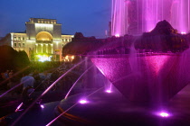 Romania, Timis, Timisoara, Colourfully lit fountain and Opera House/National Theatre illuminated at nighti, Piata Victoriei , old town.