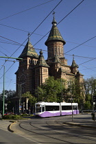 Romania, Timis, Timisoara, Modern tram passing Metropolitan Orthodox Cathedral, old town.