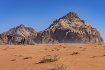 Jordan, Wadi Rum Protected Area, Blowing desert sand and mountains in the Wadi Rum Protected Area, a UNESCO World Heritage Site. Um Sahn sandstone.
