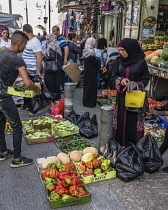 Israel, Jerusalem, East Jerusalem, A Palestinian Arab woman wearing the traditional Muslim hajib or head scarf shopping for fresh produce on Nablus Street by the Damascus Gate.