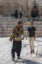 Israel, Jerusalem, East Jerusalem, A Palestinian Arab man with his copper teapot on his back sells a cold drink made of tamarind juice and rose water by the Damascus Gate.