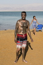 Israel, Ein Bokek, Dead Sea, A man enjoys a mud bath treatment on the shore of the Dead Sea at the resort of Ein Bokek in Israel.