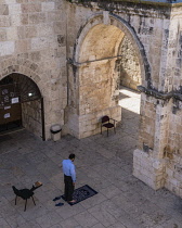 Israel, Jerusalem, A Muslim man prepares to kneel on his prayer rug and offer prayers by the inside of the East Gate or Golden Gate of the Temple Mount or al-Haram ash-Sharif in the Old City. The Old...