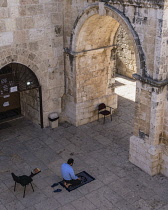 Israel, Jerusalem, A Muslim man kneels on his prayer rug to offer prayers by the inside of the East Gate or Golden Gate of the Temple Mount or al-Haram ash-Sharif in the Old City. The Old City of Jeru...