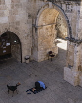 Israel, Jerusalem, A Muslim man kneels on his prayer rug and offers prayers by the inside of the East Gate or Golden Gate of the Temple Mount or al-Haram ash-Sharif in the Old City. The Old City of Je...