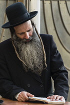 Israel, Jerusalem, Western Wall, A Haredic Jewish man studies the scriptures at the Western Wall of the Temple Mount in the Jewish Quarter of the Old City. The Old City of Jerusalem and its Walls is a...