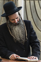 Israel, Jerusalem, Western Wall, A Haredic Jewish man studies the scriptures at the Western Wall of the Temple Mount in the Jewish Quarter of the Old City. The Old City of Jerusalem and its Walls is a...