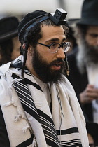 Israel, Jerusalem, Western Wall, An Haredic Jewish man in the traditional tallit - prayer shawl -and tellifin or phylactery chants in worship at the Western Wall of the Temple Mount in the Jewish Quar...