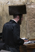 Israel, Jerusalem, Western Wall, A Hasidic Jewish man in his traditional shtreimel or fur hat worships at the synagogue beneath Wlison's Arch at the Western Wall of the Temple Mount in the Jewish Quar...