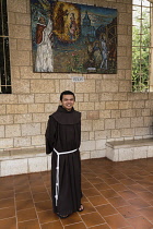 Israel, Galilee, Nazareth, A young Franciscan monk in the plaza in front of the or Basilica of the Annunciationl. Behind him is a mosaic donated by the Vatican.