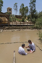 Palestine, Occupied Palestinian Territory, Qasr el Yahud, Christian pilgrims being baptized in the River Jordan at Qasr el Yahud on the Palestine side of the river in the Occupied Territory of the Wes...