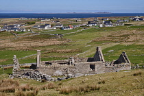 Ireland, County Donegal, Bloody Foreland, Ruined house with housing, sea and Tory Island in the background.