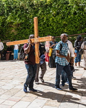 Israel, Jerusalem, Christian pilgrims preparing to walk the Via Dolorosa with a wooden cross begin at the Convent of the Sisters of Zion in the Muslim Quarter of the Old City. The Old City of Jerusale...