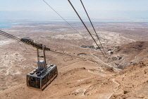 Israel, The cable car up to the ruins of the fortress of Masada in the Judean Desert of Israel. Masada National Park is a UNESCO World Heritage Site. The ruins of a former Roman encampment are visible...