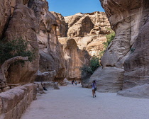 Jordan, Petra, Tourists hike into a narrow slot canyon called the Siq to see the ruins of the Nabataean city of Petra in the Petra Archeological Park is a Jordanian National Park and a UNESCO World He...