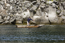 Guatemala, Solola Department, Santiago Atitlan, A Mayan man in traditional dress paddles his cayuco on Lake Atitlan near Santiago Atitlan, Guatemala.