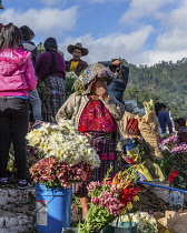 Guatemala, El Quiche Department, Chichicastenango, Quiche Mayan woman in traditional dress selling flowers on the steps of the Church of Santo Tomas.