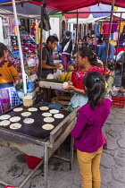 Guatemala, El Quiche Department, Chichicastenango, A Quiche Mayan woman makes tortillas in a food stall at the Indian market.