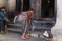 Guatemala, El Quiche Department, Chichicastenango, A Quiche Mayan woman burns incense to the Mayan gods on the steps of the Church of Santo Tomas. She is swinging a can of smoking, burning incense as...
