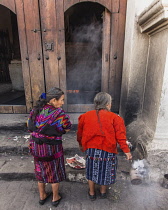 Guatemala, El Quiche Department, Chichicastenango, Two Quiche Mayan woman burn copal incense to the Mayan gods on the steps of the Church of Santo Tomas. They are swinging cans of smoking, burning res...