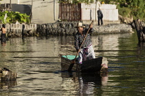 Guatemala, Solola Department, San Pedro la Laguna, A Tzutujil Mayan man in the traditional dress of San Pedro la Laguna paddles his cayuco or fishing canoe on Lake Atitilan.