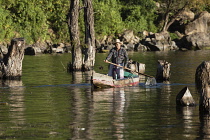 Guatemala, Solola Department, San Pedro la Laguna, A Tzutujil Mayan man in the traditional dress of San Pedro la Laguna paddles his cayuco or fishing canoe on Lake Atitilan.