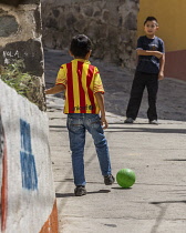 Guatemala, Solola Department, Santa Cruz la Laguna, Two young boys play soccer or football in the street.