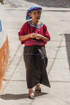 An older Cakchiquel Mayan woman in traditional dress walks down the street in Santa Cruz la Laguna, Guatemala.