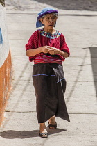 An older Cakchiquel Mayan woman in traditional dress walks down the street in Santa Cruz la Laguna, Guatemala.