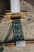 Guatemala, Solola Department, San Pedro la Laguna, A partially-finished woven belt or faja with a traditional quetzal design on a backstrap loom in a house.